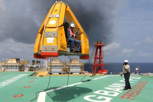 An oil worker is transferred via a 'Frog' basket from the tugboat Bourbon Auroch, operated by Bourbon SA, onto the deck of the Agbami floating production, storage and offloading vessel (FPSO), operated by Chevron Corp., in the Agbami deepwater oilfield in the Niger Delta, Nigeria, on Monday, Nov. 16, 2015. Nigeria plans to review agreements for deep offshore oil production to seek more favorable terms in line with the latest industry standards, state-owned Nigerian National Petroleum Corp. said. Photographer: George Osodi/Bloomberg via Getty Images