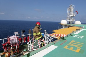 A firefighter sits on the edge of the helideck as he waits for a helicopter to arrive on the Agbami floating production, storage and offloading vessel (FPSO), operated by Chevron Corp., in the Agbami deepwater oilfield in the Niger Delta, Nigeria, on Monday, Nov. 16, 2015. Nigeria plans to review agreements for deep offshore oil production to seek more favorable terms in line with the latest industry standards, state-owned Nigerian National Petroleum Corp. said. Photographer: George Osodi/Bloomberg via Getty Images